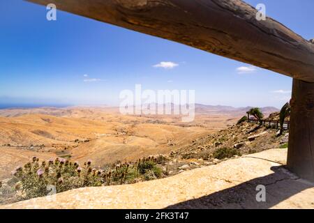 Blick auf ein Wüstental auf Fuerteventura zwischen der Sturzbarriere und der Befestigung einer Bergstraße Stockfoto