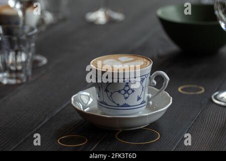 Prozess der Zubereitung von Espresso mit der Kaffeemaschine. Cappuccino in einer schönen Tasse im Landhausstil Stockfoto