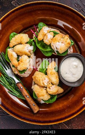 Sandwiches mit gebratenen Garnelen, Garnelen, Spinat und Mangold-Salat auf einem rustikalen Teller. Dunkler Hintergrund. Draufsicht Stockfoto