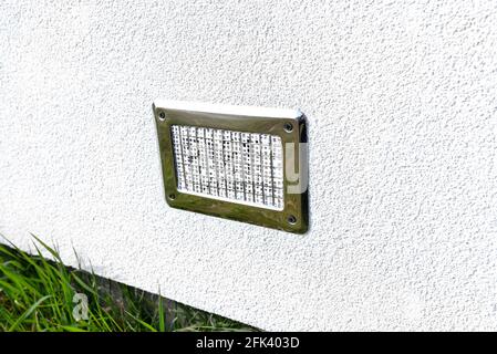 Luftansaugung aus dem Herrenhaus zum Kamin mit geschlossener Brennkammer, silbernem Gitter an der Fassade des Gebäudes. Stockfoto