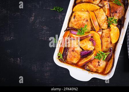 Gebackene Hähnchenschenkel. Appetitliche Scheiben gebackenes Huhn mit roten Zwiebeln und Orangen in einer Auflaufform. Draufsicht, Kopierbereich Stockfoto