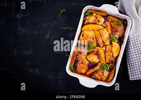 Gebackene Hähnchenschenkel. Appetitliche Scheiben gebackenes Huhn mit roten Zwiebeln und Orangen in einer Auflaufform. Draufsicht, Kopierbereich Stockfoto