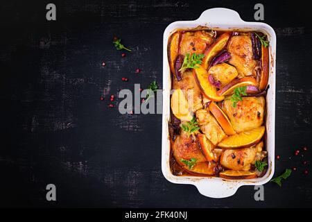 Gebackene Hähnchenschenkel. Appetitliche Scheiben gebackenes Huhn mit roten Zwiebeln und Orangen in einer Auflaufform. Draufsicht, Kopierbereich Stockfoto