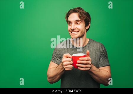Der Mann trinkt einen Instant-Kaffee, isoliert auf grünem Hintergrund Stockfoto