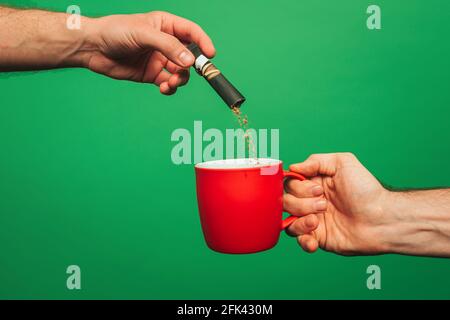 Nahaufnahme Mann bereitet einen Instant-Kaffee, isoliert auf grünem Hintergrund Stockfoto