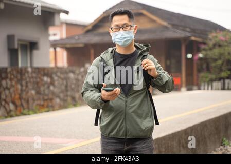 Der junge Backpacker-Mann reist allein und nutzt Smartphone, um mit Maske, Brille einen Weg zu finden. Stockfoto