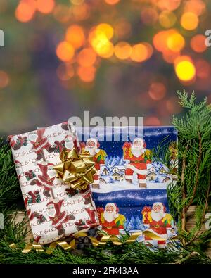 Eingewickelte Weihnachtsgeschenke in der Nähe von Nadelbäumen mit goldenen Lichterketten Bokeh-Hintergrund Stockfoto