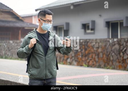 Der junge Backpacker-Mann reist allein und nutzt Smartphone, um mit Maske, Brille einen Weg zu finden. Stockfoto