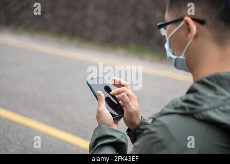 Der junge Backpacker-Mann reist allein und nutzt Smartphone, um mit Maske, Brille einen Weg zu finden. Stockfoto