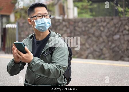Der junge Backpacker-Mann reist allein und nutzt Smartphone, um mit Maske, Brille einen Weg zu finden. Stockfoto