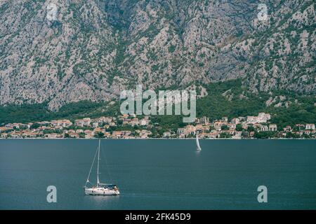 Weiße Segelyacht segelt auf der Kotor Bucht gegen die Hintergrund der Stadt in den Bergen Stockfoto