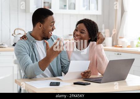 Porträt Von Glücklich Aufgeregt Schwarz Verheiratete Paar Lesen Versicherungsdokumente In Der Küche Stockfoto