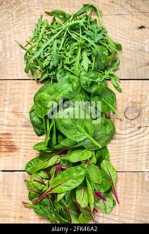 Salatblätter, Arugula, Spinat und Swiis Chard mischen. Holzhintergrund. Draufsicht Stockfoto