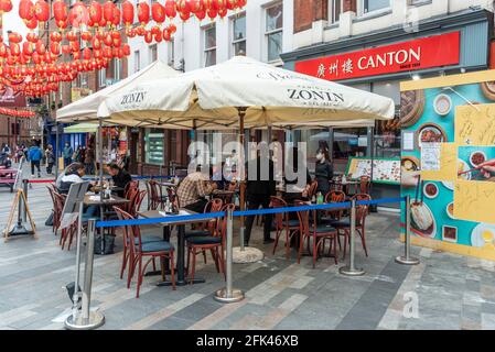 London, Großbritannien. 28. April 2021. UK Wetter: Menschen speisen außerhalb von Restaurants in Chinatown, da Einschränkungen durch Coronaviren das Essen im Inneren vorerst verhindern. Restaurantbesitzer haben Vordächer installiert, um bei schlechtem Wetter Schutz zu bieten, aber die üblichen Duschen im April waren in diesem Jahr selten. Es wird jedoch erwartet, dass in dieser Woche Regen eintreffen wird. Kredit: Stephen Chung / Alamy Live Nachrichten Stockfoto