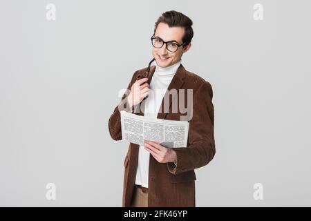 Fröhlicher Mann mit Zeitung und rauchender Pfeife, der die Kamera ansah Isoliert auf Grau Stockfoto