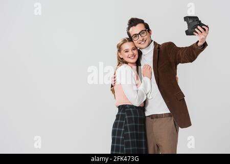 Junges, altmodisches Paar, das Selfie auf einer Vintage-Kamera macht, isoliert auf Grau Stockfoto