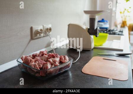 Nahaufnahme von weiblichen Händen, die Fleisch mit einem Messer auf einem Schneidebrett in Stücke schneiden, um Hackfleisch zu kochen. Stockfoto