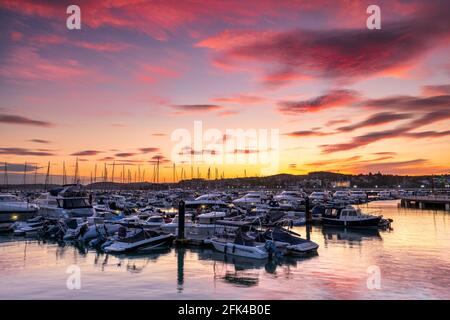 Torquay, South Devon, England. Nach einem Tag Sonnenschein und Duschen an der Südküste, wenn die Sonne untergeht, leuchtet ein farbenfroher Himmel das ruhige Wasser von Th auf Stockfoto