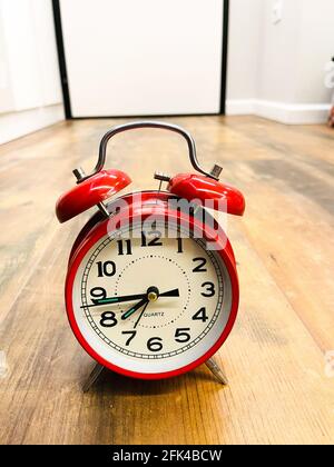 Roter Wecker auf Holzfußboden. Zeitkonzept. Stockfoto