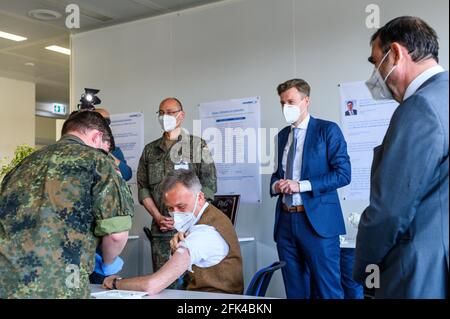 Schwarzenbach An Der Saale, Deutschland. April 2021. Bayerns Gesundheitsminister Klaus Holetschek (CSU, r) beobachtet die Impfung von Stefan Hermann (Mitte, unten) aus der Produktentwicklungsabteilung der Sandler AG. Im Hintergrund sind General Thomas Hambach (2. V.l.), Kommandeur des Bayerischen Staatskommandos der Bundeswehr, und Landrat Oliver Bär (CSU, 2. V.r.) zu sehen. Bei der Sander AG werden die Mitarbeiter ab Mittwoch gegen Covid-19 geimpft. Quelle: Daniel Vogl/dpa/Alamy Live News Stockfoto