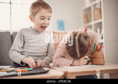 Kinder sitzen auf dem Sofa und spielen mit Modelliermasse und mit Farben. Stockfoto
