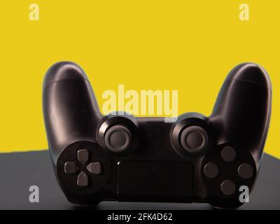 Steuerung von elektronischen Spielen der neuen Generation. Schwarzer Gamecontroller auf blauem Hintergrund isoliert. Gamepad. Kabelloses Spielchen für PC-Spiele. Stockfoto