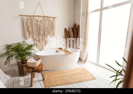 Gemütliches, modernes, minimalistisches Badezimmer mit großer weißer Badewanne im Innenbereich Stockfoto