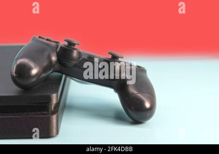 Steuerung von elektronischen Spielen der neuen Generation. Schwarzer Gamecontroller auf blauem Hintergrund isoliert. Gamepad. Kabelloses Spielchen für PC-Spiele. Stockfoto
