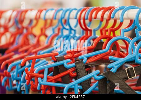 Viele bunte Kleiderbügel aus Kunststoff an Kleiderstange aus der Nähe. Ladenkonzept, Verkauf, Design, leerer Kleiderbügel Stockfoto