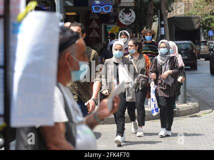 Beirut, Libanon. April 2021. Menschen mit Gesichtsmasken gehen in Beirut, Libanon, 28. April 2021. Gesundheitsexperten sagten, dass der Libanon im Kampf gegen COVID-19 immer noch vor mehreren Herausforderungen steht. Firas Abiad, Direktor des Universitätskrankenhauses Rafic Hariri, sagte gegenüber Xinhua, dass eine der wichtigsten Herausforderungen für den Libanon die Ungenauigkeit bei der Anzahl der Infektionen im Land sei, da Menschen dazu neigen, PCR-Tests zu vermeiden, wenn sie keine Symptome des Virus zeigen. Quelle: Bilal Jawich/Xinhua/Alamy Live News Stockfoto