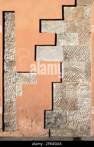 Alte schäbig aussehende Wand aus Marmorblöcken mit Kerben, teilweise verputzt. Pisa. Italien. Stockfoto