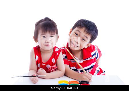 Kleine asiatische (thailändische) Kinder glücklich, Bruder und Schwester schauen auf die Kamera und lächeln, halten einen Pinsel, Konzepte der Kreativität und Bildung Stockfoto