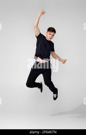 Hübscher junger Mann in schwarzem T-Shirt, der springt. Stockfoto