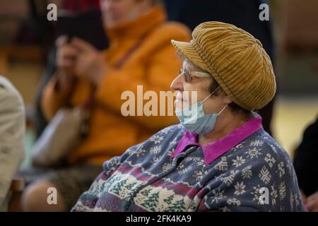 Treffen Club der Älteren. Eine ältere Frau in einer medizinischen Maske bei einem Ereignis während einer Coronavirus-Infektion. Stockfoto