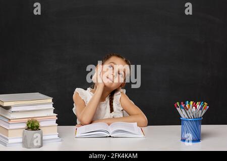 Glückliches Schulmädchen, das im Klassenzimmer am Tisch sitzt Stockfoto