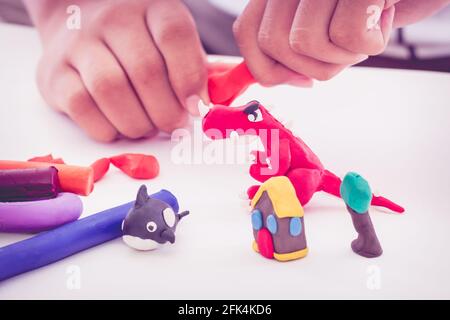 Kind spielt und kreiert Spielzeug aus Spielteig. Kinder modellieren Ton. Stärken Sie die Phantasie des Kindes. Vintage-Stil. Stockfoto