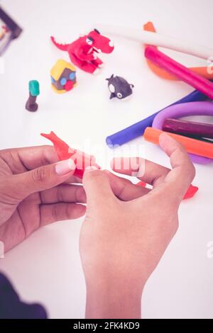 Kind spielt und kreiert Spielzeug aus Spielteig. Kinder modellieren Ton. Stärken Sie die Phantasie des Kindes. Vintage-Stil. Stockfoto