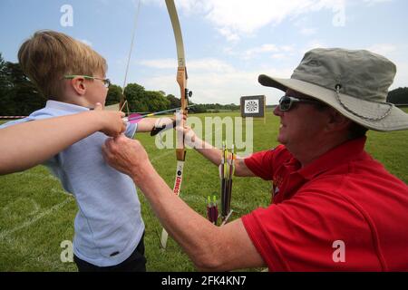 Ayr Archery Club veranstaltete einen Tag der offenen Tür „Kommen Sie und versuchen Sie es mit dem Bogenschießen“ im J.Mowatt Playing Fields Doonside, der 5jährige Lewis Flynn erhält Anweisungen von Willie Roney Stockfoto