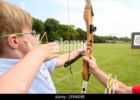 Ayr Archery Club veranstaltete einen Tag der offenen Tür „Kommen Sie und versuchen Sie Bogenschießen“ am J.Mowatt Playing Fields Doonside, der 5jährige Lewis Flynn von Ayr erhält Anweisungen von Willie Roney, während er seinen Pfeil loslässt Stockfoto