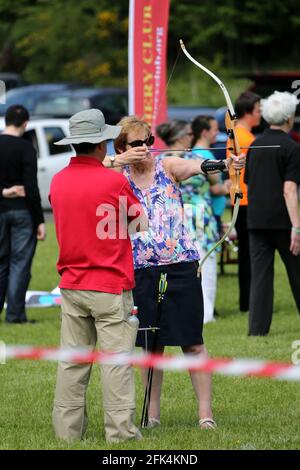 Ayr Archery Club veranstaltete einen Tag der offenen Tür „Kommen Sie und versuchen Sie Bogenschießen“ auf der J.Mowatt Playing Fields Doonside, Ayr Moira Jones zielt auf das Ziel unter dem wachsamen Auge von Willie Roney Stockfoto