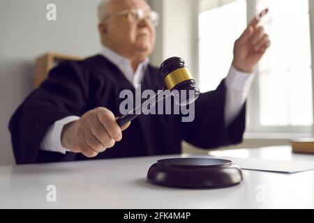 Nahaufnahme der Hand eines reifen Richters, der mit einem Holzklotz auf den Schallblock trifft Gavel vor Gericht Stockfoto