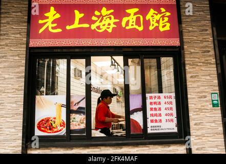 Straßenfenster des Old Shanghai Noodle House mit einem Koch, der hinter der Huanghe Road, einer Lebensmittelstraße, im Huangpu District von Shanghai, China, arbeitet. Stockfoto