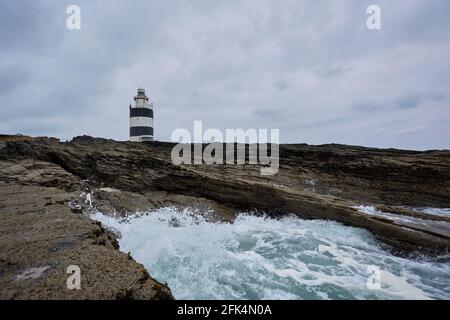 Riesige Meeresgewässer, die am Hook Lighthouse über Felsen toben. Wexford, Irland. Stockfoto