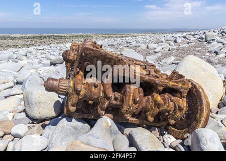 Die rostigen Überreste eines Fahrzeugmotors am steinigen Strand von Kilve, Somerset, Großbritannien Stockfoto