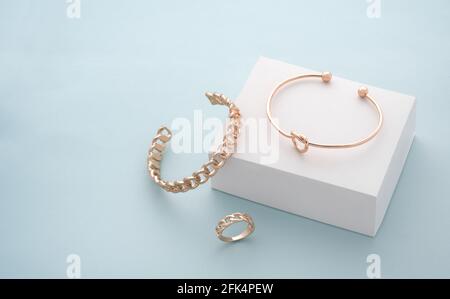 Moderne goldene Armbänder und Ring auf weißem und blauem Hintergrund Stockfoto