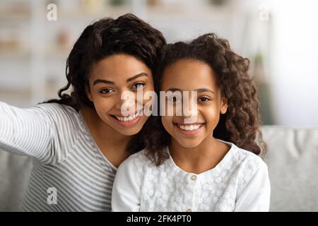 Fröhliche schwarze Mutter und Tochter, die zu Hause Selfie machen Stockfoto