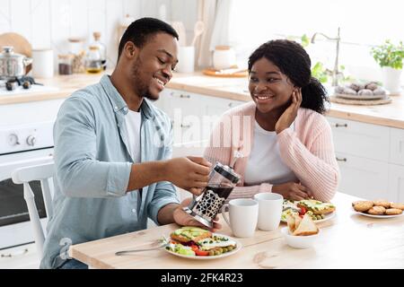 Inländische Freizeit. Millennial Schwarzes Paar Sitzt Am Tisch, Mit Frühstück In Der Küche Stockfoto