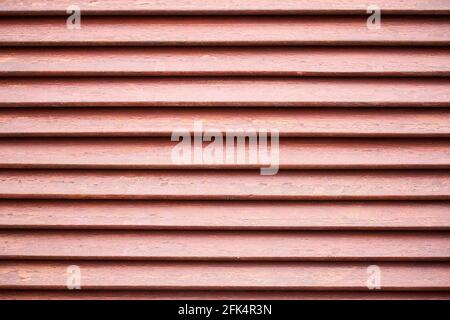 Rotbrauner Holzhintergrund mit den geraden schwarzen Schatten zwischen den Brettern. Stockfoto