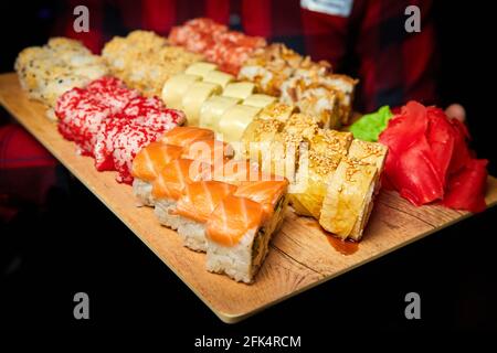 Big set of sushi rolls on a board in the hands of a waiter Stockfoto