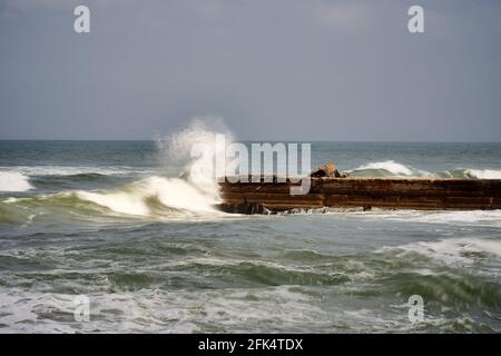 Ein Stück alte verlassene Pier während des Seesturms. Wellen an einem trüben, bösen Tag. Stockfoto